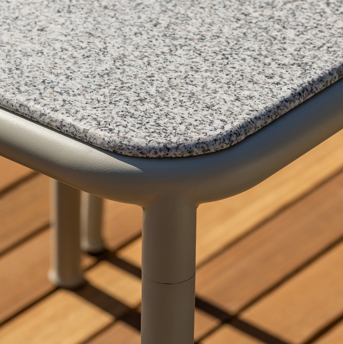 Corner detail of the Campus table in Pebble grey with a light granite top on a wooden slatted floor