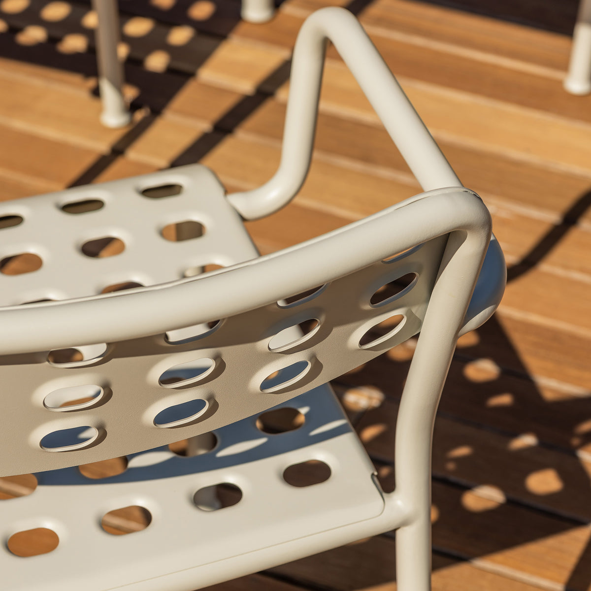 Detail of an Aeros armchair showing the pressed metal back and the hole detail on the seat and back which is casting a beautiful shadow on the floor