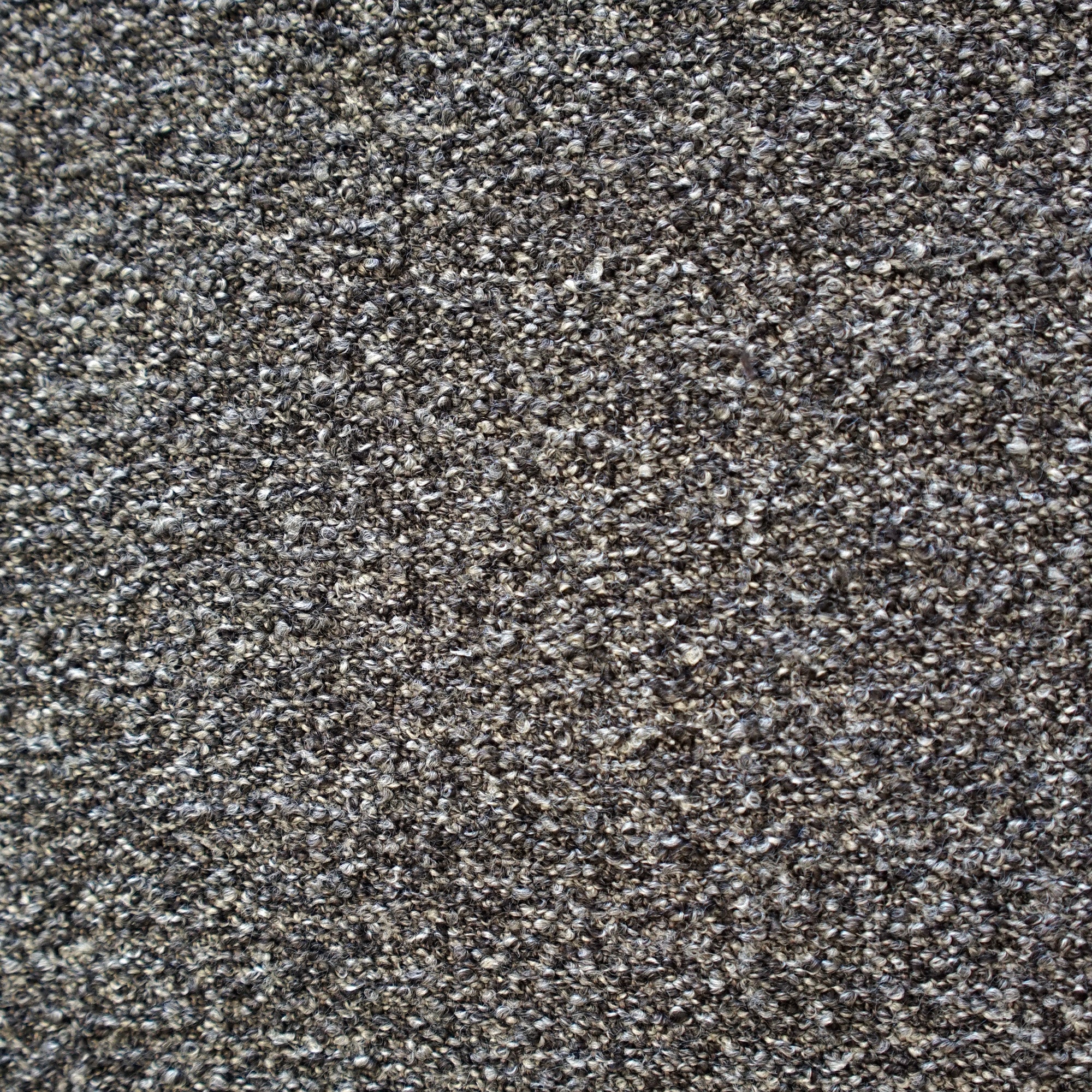 A close-up texture shot of a dense, tightly knotted Boucle fabric in a dark grey and black colorway | Case Furniture