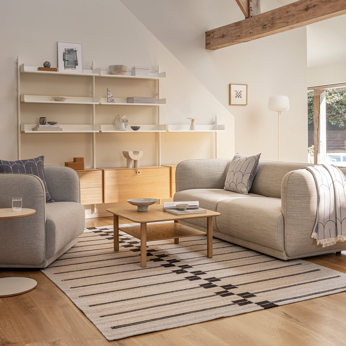 Meris 2 Seat sofa and Armchair by Monica Armani in light fabrics with a Slot shelving in white with a combination of oak cabinets in a modern barn conversion house. 