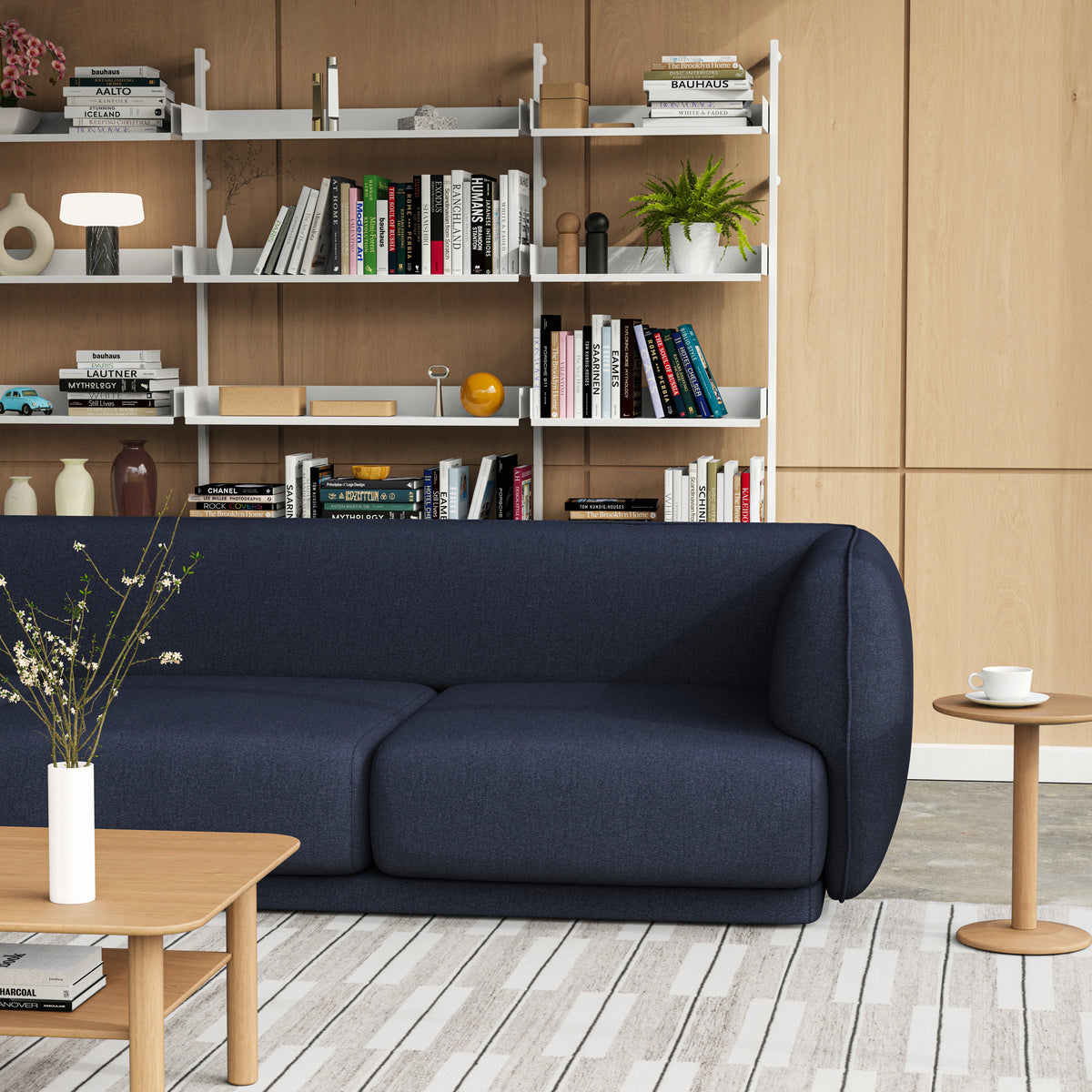 Meris 3 seat Sofa in Mode Society fabric set in a styled living room with Port side and coffee tables in Oak and a light wood wall panelling, Slot shelving run in White, and a concrete floor