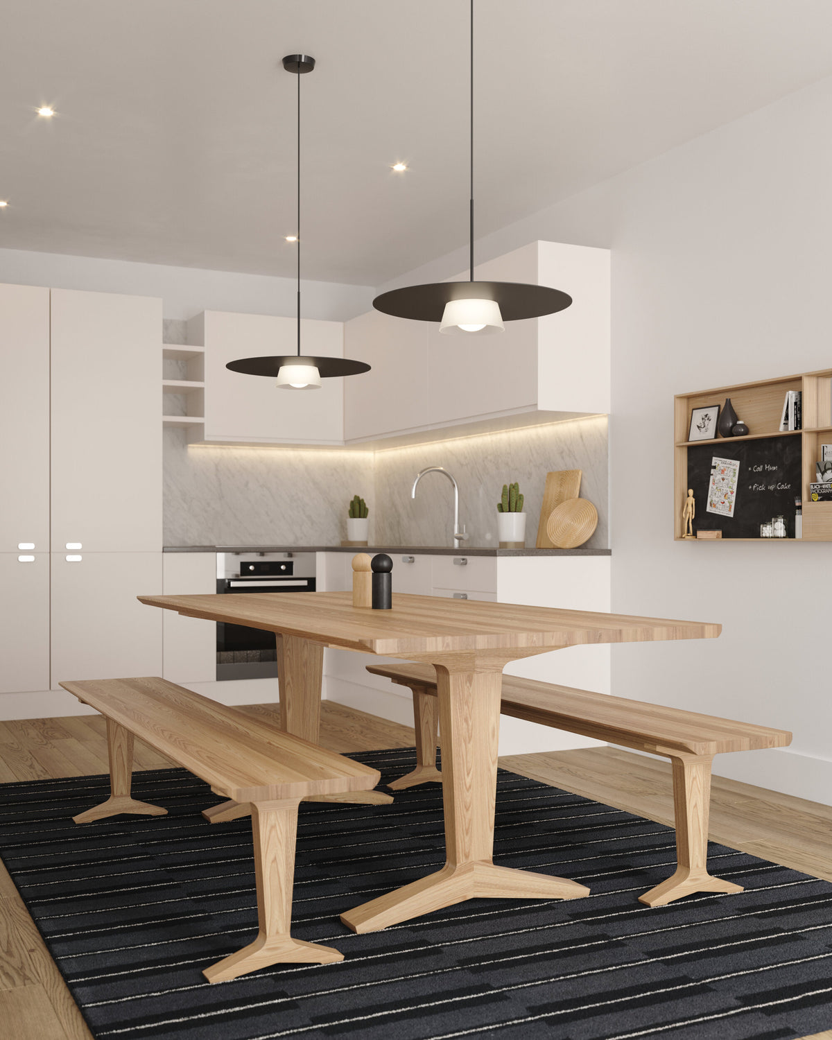 A modern dining area featuring a light oak wood table with matching bench seats, set on a dark striped area rug. The space is lightened by the sculptural Sum Pendant.