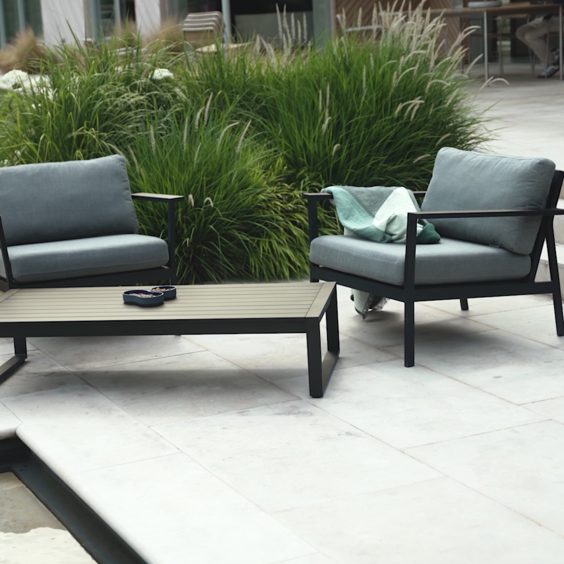 slow rotation video of the Eos Sofa Armchair and Coffee table in black in a poolside setting